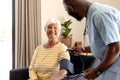 African american male health worker checking blood pressure of caucasian senior woman at home Royalty Free Stock Photo