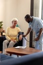 African american male health worker checking blood pressure of caucasian senior woman at home