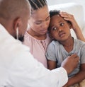 African american male paediatrician examining sick boy with stethoscope during visit with mom. Doctor checking heart Royalty Free Stock Photo