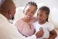 African american male paediatrician examining sick girl with stethoscope during visit with mom. Doctor checking heart Royalty Free Stock Photo