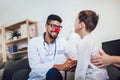 African American male pediatrician with stethoscope and clown nose talking to boy