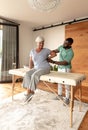 African american male physiotherapist giving back massage therapy to caucasian senior woman at home Royalty Free Stock Photo