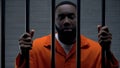 African-american male prisoner holding bars and looking to camera, imprisonment Royalty Free Stock Photo