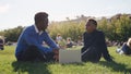 African-American male professor discussing exam results with student sitting on lawn near school