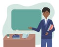 African american male school or university teacher or professor standing next to classroom chalkboard at blackboard in classroom. Royalty Free Stock Photo