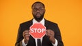 African-american male showing stop sign, antiracism campaign, social equality