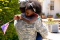 African American male soldier holding his daughter with a US flag in his arms