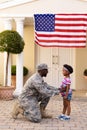 African american male soldier kneeling and greeting daughter at house entrance