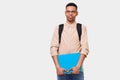 African American male student in casual outfit with blue folder with papers holding in hand, with backpack smiling and looking to Royalty Free Stock Photo