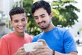 African american male student with typical hairstyle in cityTwo hispanic guys showing pictures on phone Royalty Free Stock Photo