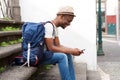 African american male tourist sitting on stairs with bag and mobile phone Royalty Free Stock Photo