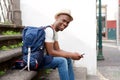 African american male tourist sitting on steps with bag and mobile phone Royalty Free Stock Photo