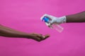 African American male wearing sanitary gloves pouring hand sanitizer in a female's hands