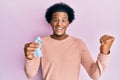 African american man with afro hair holding pink cancer ribbon screaming proud, celebrating victory and success very excited with Royalty Free Stock Photo