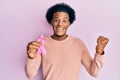 African american man with afro hair holding pink cancer ribbon screaming proud, celebrating victory and success very excited with Royalty Free Stock Photo