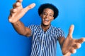 African american man with afro hair wearing casual clothes looking at the camera smiling with open arms for hug Royalty Free Stock Photo