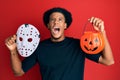 African american man with afro hair wearing hockey mask and halloween pumpking angry and mad screaming frustrated and furious, Royalty Free Stock Photo