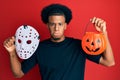 African american man with afro hair wearing hockey mask and halloween pumpking depressed and worry for distress, crying angry and