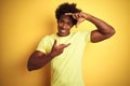 African american man with afro hair wearing t-shirt standing over isolated yellow background smiling making frame with hands and
