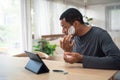 African American man applying cream on his face and using digital tablet pretend to be mirror before shaving his beard Royalty Free Stock Photo