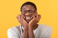 African american man biting nails in panic on yellow studio background. Horrified black guy feeling afraid or nervous Royalty Free Stock Photo