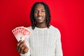 African american man with braids holding 20 israel shekels banknotes looking positive and happy standing and smiling with a