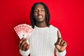 African american man with braids holding 20 israel shekels banknotes smiling with an idea or question pointing finger with happy