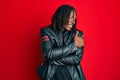 African american man with braids wearing black leather jacket hugging oneself happy and positive, smiling confident Royalty Free Stock Photo