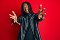 African american man with braids wearing black leather jacket looking at the camera smiling with open arms for hug Royalty Free Stock Photo