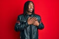 African american man with braids wearing black leather jacket smiling with hands on chest, eyes closed with grateful gesture on Royalty Free Stock Photo