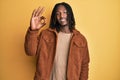 African american man with braids wearing brown retro jacket smiling positive doing ok sign with hand and fingers