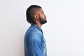 African american man with braids wearing denim shirt over isolated white background looking to side, relax profile pose with Royalty Free Stock Photo