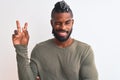 African american man with braids wearing green sweater over isolated white background smiling with happy face winking at the Royalty Free Stock Photo