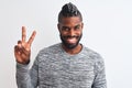 African american man with braids wearing grey sweater over isolated white background smiling with happy face winking at the camera Royalty Free Stock Photo