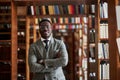 An African American man in a business suit standing in a library in the reading room. Royalty Free Stock Photo