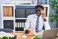 African american man business worker talking on smartphone reading notebook at office Royalty Free Stock Photo
