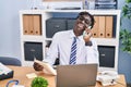 African american man business worker talking on smartphone reading notebook at office Royalty Free Stock Photo