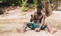 African American man cracking open a coconut with a stone on the beach