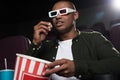 african american man in 3d glasses eating popcorn and watching movie