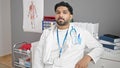 African american man doctor sitting on table relaxed at clinic Royalty Free Stock Photo