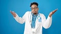 African american man doctor standing clueless over isolated blue background Royalty Free Stock Photo