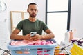 African american man doing laundry using smartphone puffing cheeks with funny face Royalty Free Stock Photo