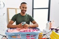 African american man doing laundry using smartphone smiling and laughing hard out loud because funny crazy joke Royalty Free Stock Photo