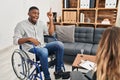 African american man doing therapy sitting on wheelchair pointing finger up with successful idea Royalty Free Stock Photo