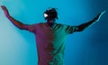 African American man dons VR glasses, engrossed in a virtual reality simulation, gesturing with hands, against a