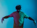 African American man dons VR glasses, engrossed in a virtual reality simulation, gesturing with hands, against a