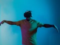 African American man dons VR glasses, engrossed in a virtual reality simulation, gesturing with hands, against a