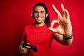 African american man with dreadlocks playing video game using joystick and headphones doing ok sign with fingers, excellent symbol Royalty Free Stock Photo