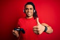 African american man with dreadlocks playing video game using joystick and headphones happy with big smile doing ok sign, thumb up Royalty Free Stock Photo