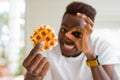 African american man eating sweet Belgian waffle with happy face smiling doing ok sign with hand on eye looking through fingers Royalty Free Stock Photo